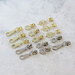 Assorted metal zipper pulls in nickel and gold, displayed neatly on a white countertop.