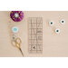 The sew trim ruler staged on a table with sewing supplies.