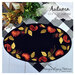 A top down shot of the Autumn Wool Mat, embroidered with elegant autumnal colors, staged on a picnic table with coordinating décor.