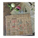 Finished cross stitch pattern next to scattered household supplies.