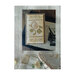 Finished cross stitch scissor box pattern on a placemat next to scissors and photos.