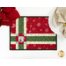 A top down close up of one of the Fat Quarter Shuffle Mats, demonstrating the Christmas fabric prints and colors; flowers and a plate with a napkin peek into frame.