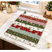 The completed Dry Ideas drying mat, colored in red, green, and white fabrics from the Holiday Spirit collection by Riley Blake Designs, staged on a white marble kitchen counter with coordinating decor.