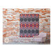 image of the finished Deco quilt staged on a brick wall next to a pale pink chair with the Lo & Behold Stitchery label.