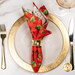 A top down shot of the napkin with the red fabric facing out, staged on a coordinating gold table setting on a white marbled table.