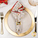 A top down shot of the napkin with the cream fabric facing out, staged on a coordinating gold table setting on a white marbled table.