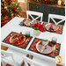Lifestyle shot of a white dining table with the four placemats staged with coordinating plates, flowers, and folded napkins.