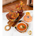 The completed Bowl Cozies, colored in warm, autumn themed prints from the Give Thanks collection by Timeless Treasures Fabrics, staged on a white marbled counter top with coordinating décor. One of the cozies holds a bowl of tomato bisque with cheese and basil.