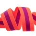 A watermelon and plum ribbon, curled and resting on a flat surface.