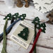 The tree lot floss drops by Primrose Cottage Stitches displayed with floss and in their packaging. 