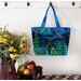 The completed tote made with a colorful nighttime forest panel, staged against a wall with coordinating flowers.