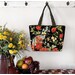 The completed tote made with a colorful floral-themed panel, staged against a wall with coordinating flowers.