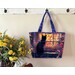 The completed tote made with a colorful cat-themed panel, staged against a wall with coordinating flowers.