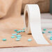 A roll of the finishing tape being used on a linen cross stitch fabric with scattered décor.