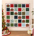 The completed Presently quilt, colored in red, green, navy, light blue, cream, and white fabrics from the When Snow Falls collection from Moda Fabrics, hung on a cream shiplap and staged with a decorated Christmas tree with presents.
