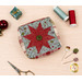 A top down shot of the Folded Star Pin Cushion Kit, colored in wintry prints from the Chilly collection by Moda Fabrics, beside the three clay pins, staged on a light wooden surface with coordinating thread and décor.