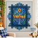 The completed Hanukkah Lights Quilt, colored in blue, yellow, green, and orange fabrics from the Hanukkah Lights collection by Northcott Fabrics, hung on a white wall and staged with coordinating décor and a festive hanukkiah/menorah.