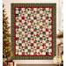 The completed Playing Favorites Quilt, colored in rich cream, red, and sage and forest green fabrics from the Candlelight Christmas collection by Moda Fabrics, hung on a cream shiplap wall and staged with understated, coordinating décor.