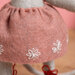 Dusty pink felt skirt with white embroidered flowers on a gray mouse.