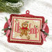 Red wooden ornament display with a mounted cross stitch design reading "Oh Snap," with a gingerbread man, holly, evergreen sprigs, pinecones, and red-and-white striped bows.