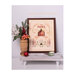 Finished Noel Ornament Sampler in a wooden frame next to a wooden vase of Christmas botanicals in a white scene.