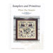 Front cover of the Winter Day Sampler showing the finished pattern in a wooden frame isolated on a quaint wooden background.