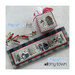 Finished Frosty Tiny Town pattern on a blue and gray plaid fabric board laid next to a square pinkeep and berry branch.