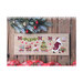 Front cover of the A Cargo of Toys cross stitch pattern showing the finished pattern laid on a wooden plank table next to ribbon and a pine bough with ornaments.
