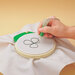 The emboridery hoop in use with a white cloth and a punch needle embroidery technique on display.
