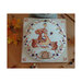 Photo of the finished Autumn Day - Squirrel cross stitch pattern laid on a wood plank table, lantern, and leaves.