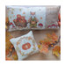 Photo of both the finished Autumn is Here cross stitch patterns laid on a wood plank table next to berries and leaves.