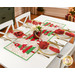 The completed Crazy Christmas Tree table runner, colored in bright red, green, and white fabrics from the Snow Time collection by Moda Fabrics, staged on a white table with four coordinating table settings with napkins, plates, and utensils.