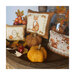 Photo of three Autumn Pillow designs surrounded by a glass vase, pumpkins, leaves, and fall berries.