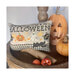 Photo of one Halloween pillow in a stand next to a pumpkin, Jack-o'-lantern, and autumnal berries.