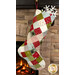 The completed Fast Fusible Patchwork Stocking colored in wintry prints from the Chilly collection by Moda Fabrics, hung on a stone fireplace with Christmas decor peeking out of the top of the stocking.
