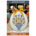The front cover of the Autumn Basket pattern showcasing the finished project featuring fall florals, pumpkins, and black birds.