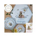 Finished cross stitch patterns of bees and bears laid on a wood table next to a bowl of applesauce.