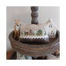 Photo of the Winter Village pattern finished on a decorative pillow next to a deer figure and a small white house.