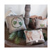 Photo of the Mittens, Deer, and Hot Cocoa patterns finished on decorative pillows in a wooden tower surrounded by pine boughs, a deer, and a small white house.