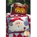 The front of the Jingle Bell Santa Pillows pattern featuring two holiday pillows, a cheery santa with a heart and a bell at the end of his cap, and two large holiday bells, on a red and white diamond quilt.