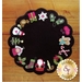 A circular black wool holiday mat featuring festive decorations along the edges, including Santa, a snowman, gingerbread cookies, candy canes, Christmas gifts, and holly. The design has a scalloped edge.