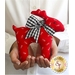 A person holding a red fabric reindeer ornament with a black and white checked bow.