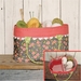 A floral fabric basket with red polka dot trim filled with various colors of yarn and knitting needles, resting on a wooden surface. An inset shows a close-up of an inner compartment organizing some yarn and tools.