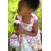 A little girls wearing the Tea Party Dress holding a flower.