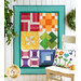 An image of a Learn To Quilt Beginner Quilt hanging on a wall surrounded by greenery.
