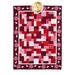 A patchwork quilt featuring a design in various shades of red and white, with a floral border.