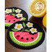 Two circular fabric coasters featuring a watermelon design with white flowers and green leaves, placed on a wooden surface next to two halves of a lemon.