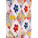 Colorful quilt featuring a patchwork design with alternating diamond shapes. Each diamond contains a blue flower with green leaves or a red flower with green leaves, set against a background of various bright fabrics in patterns like checks and polka dots.