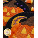 Close-up of felt Halloween decorations featuring orange and yellow pumpkins with stitched details, alongside a crescent moon design. Candy corn is visible in the background.