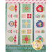 Three quilted table runners hang against a brick wall, featuring colorful patchwork designs in various geometric shapes, including stars, circles, and gift-like patterns.